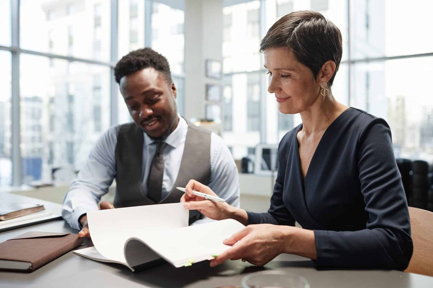 Two professionals reviewing a printed Articles of Association document in a modern office, highlighting strategic decision-making and business governance.