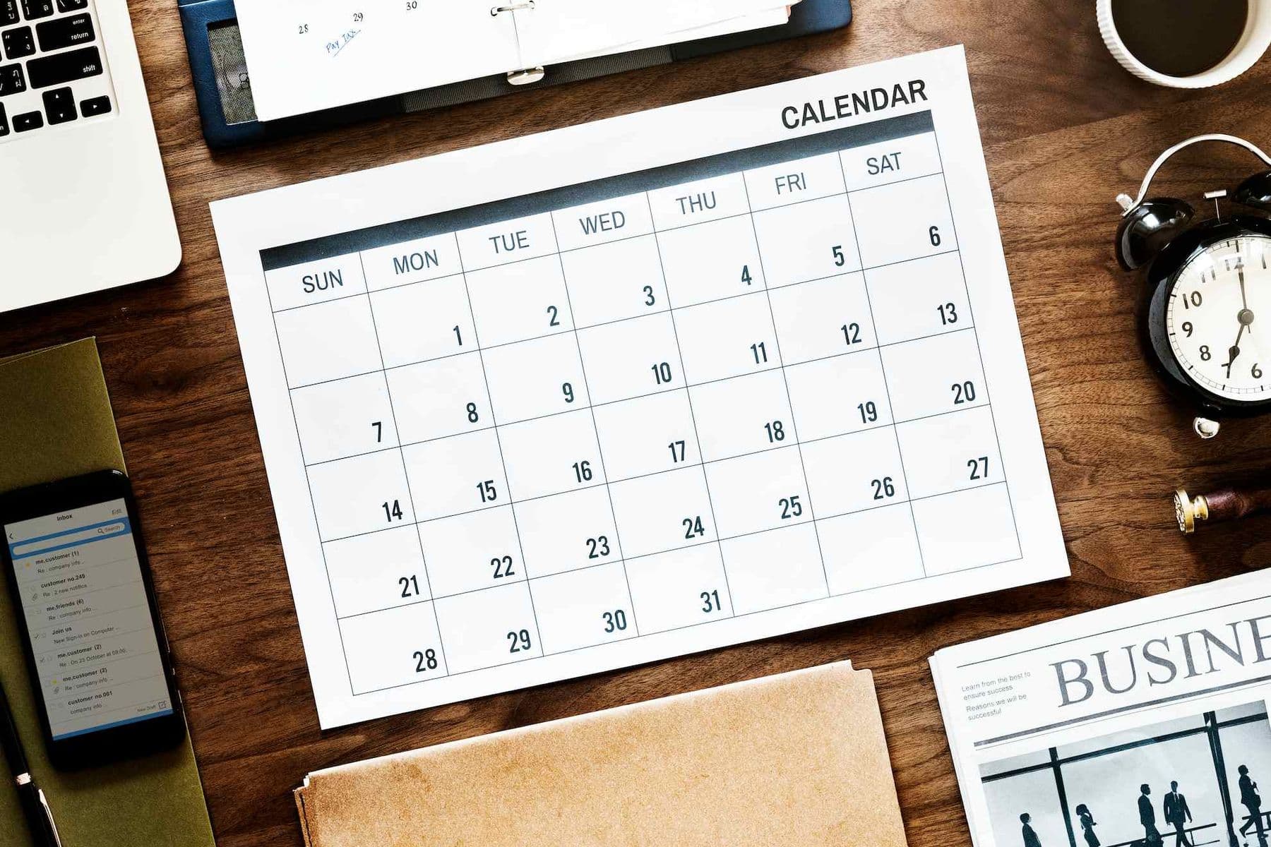 Desk with calendar, clock, and business documents with the corporate tax filing deadline marked on the calendar.