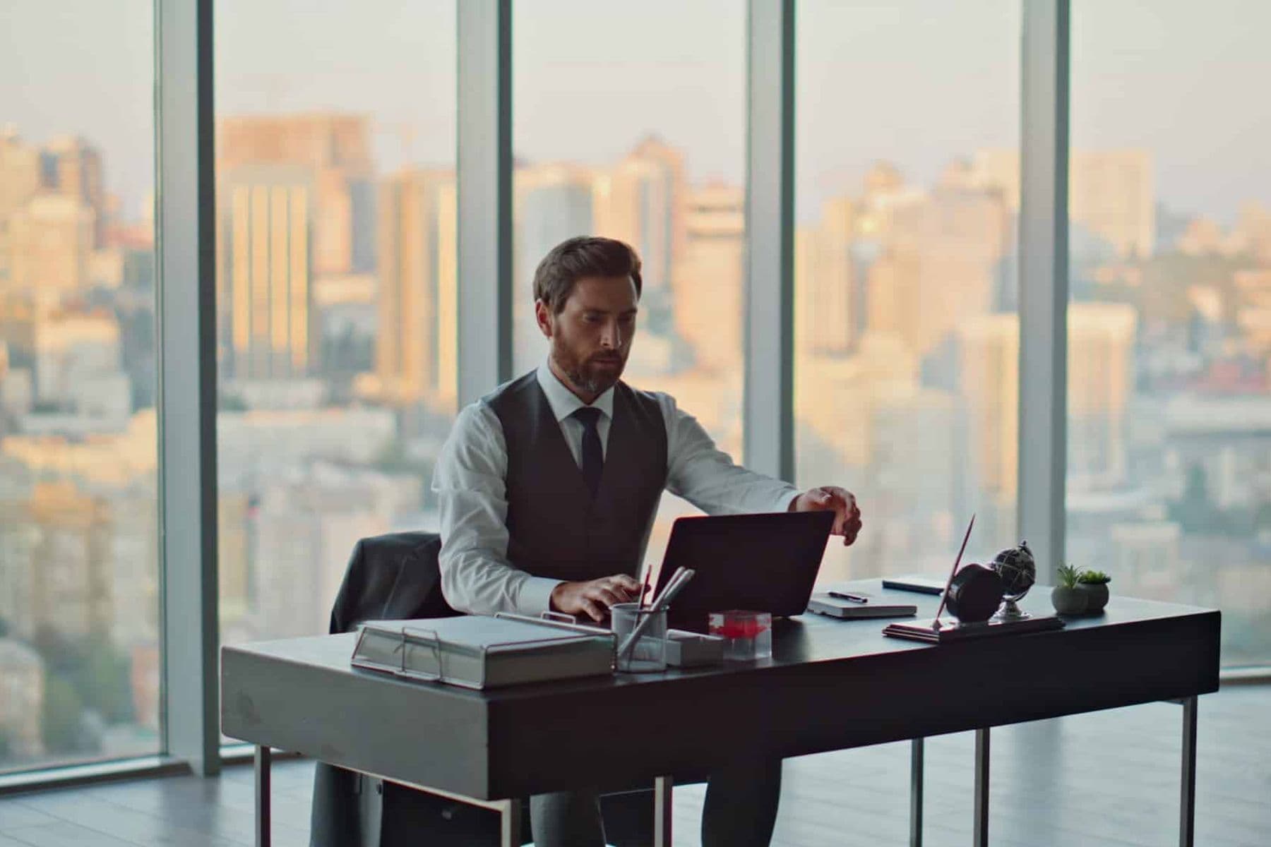Business professional in a modern UAE office reviewing VAT return documents on a laptop with a city skyline view.