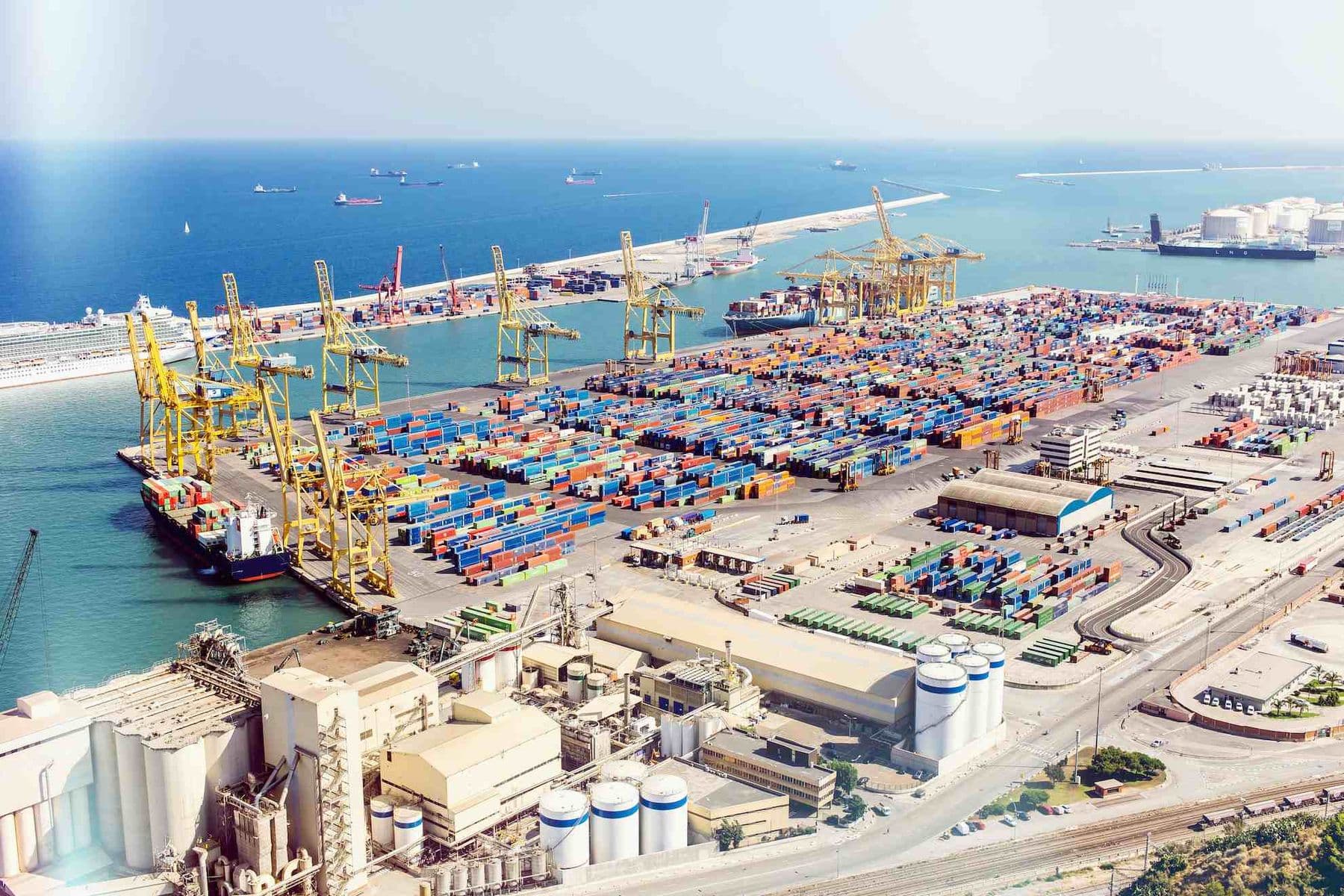 Aerial view of Jebel Ali Port in Dubai showing shipping containers, cranes, and warehouses representing UAE Designated Zones and Free Zone trade operations.