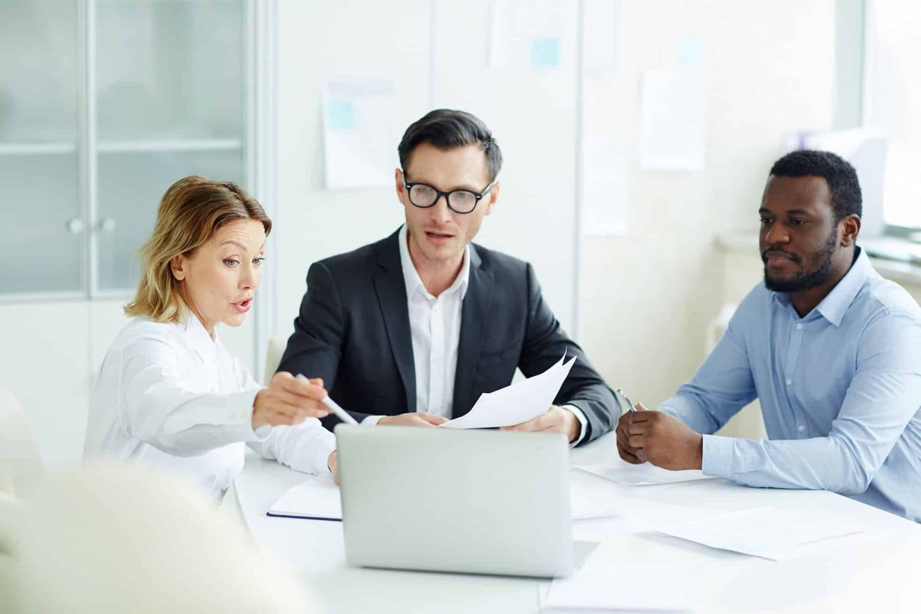 Business professionals in a UAE office discussing VAT registration and compliance documents on a laptop.