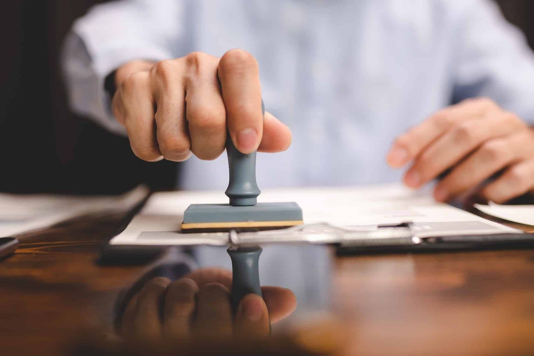 Hand applying an approval stamp on paperwork related to a Tax Clearance Certificate in the UAE.