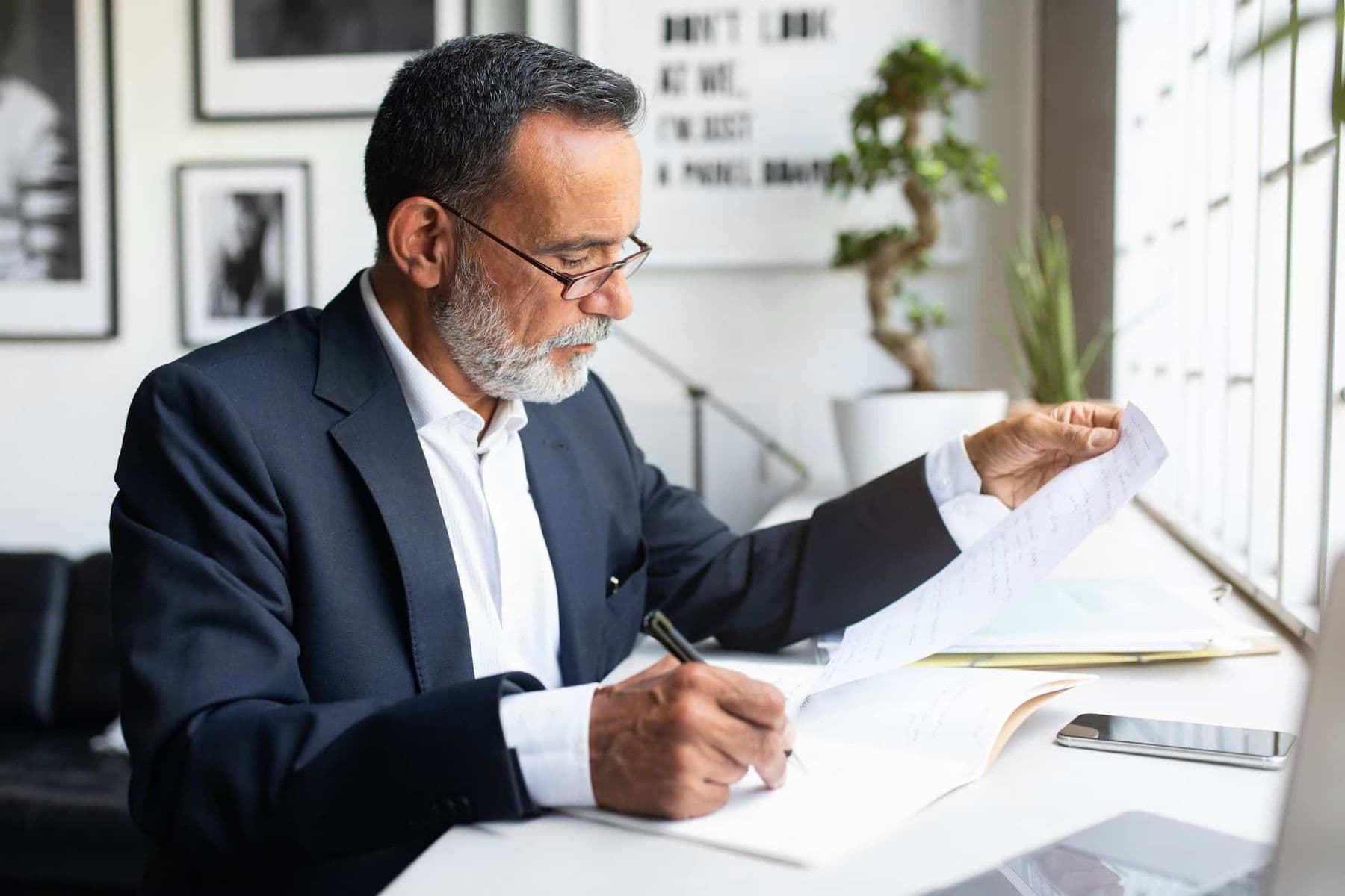 Professional business owner reviewing VAT deregistration documents in modern UAE office, preparing paperwork for Federal Tax Authority submission.