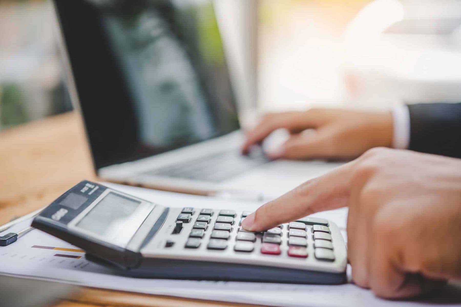 Businessperson calculating VAT payments on a calculator and laptop in UAE to avoid late payment penalties.